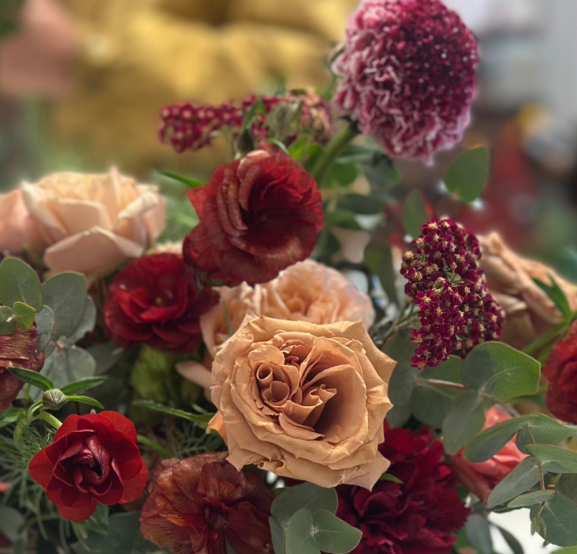 A closeup of flowers in red, toffee, and purple tones